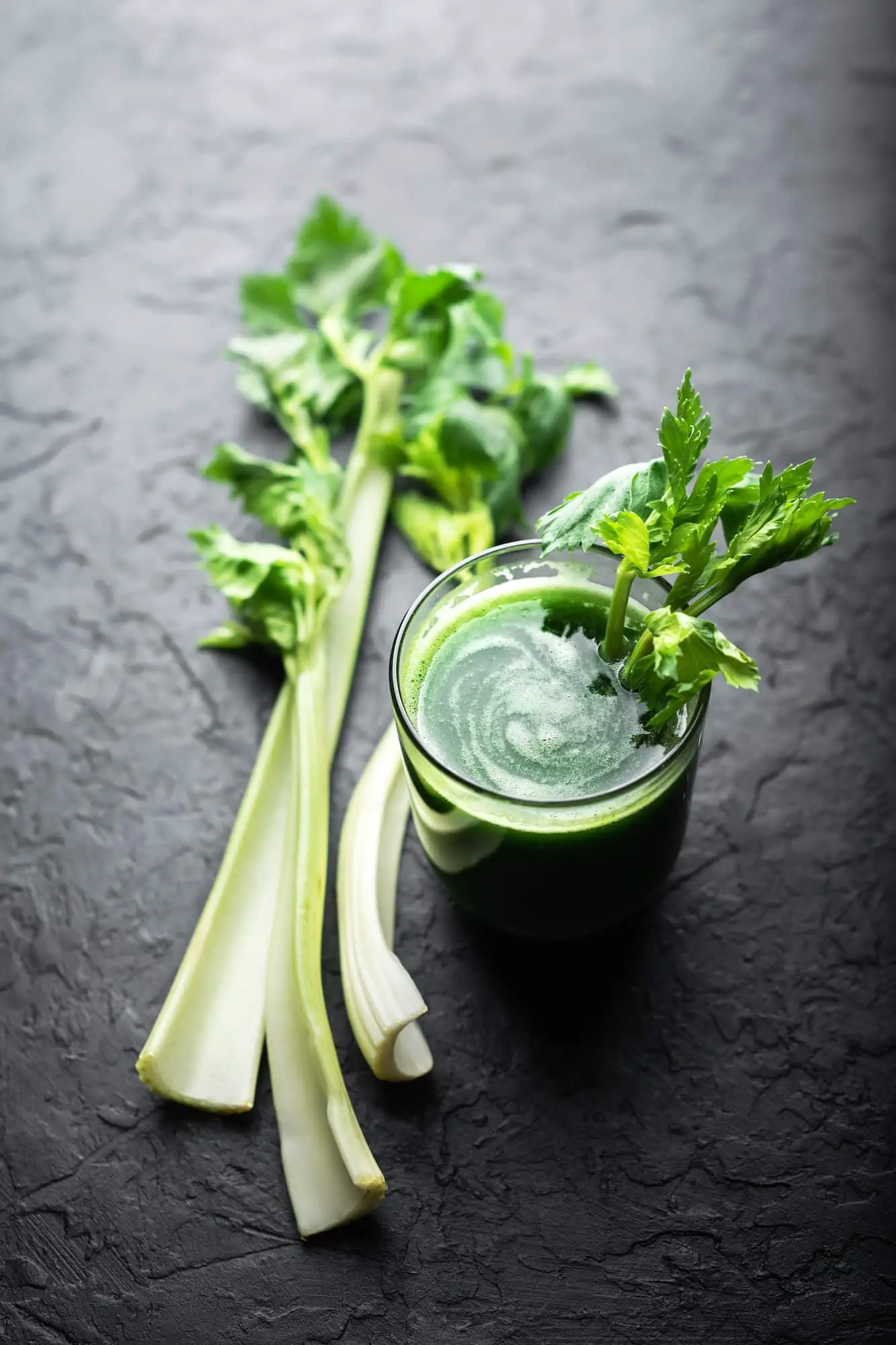 Celery fresh green juice in glass on black background